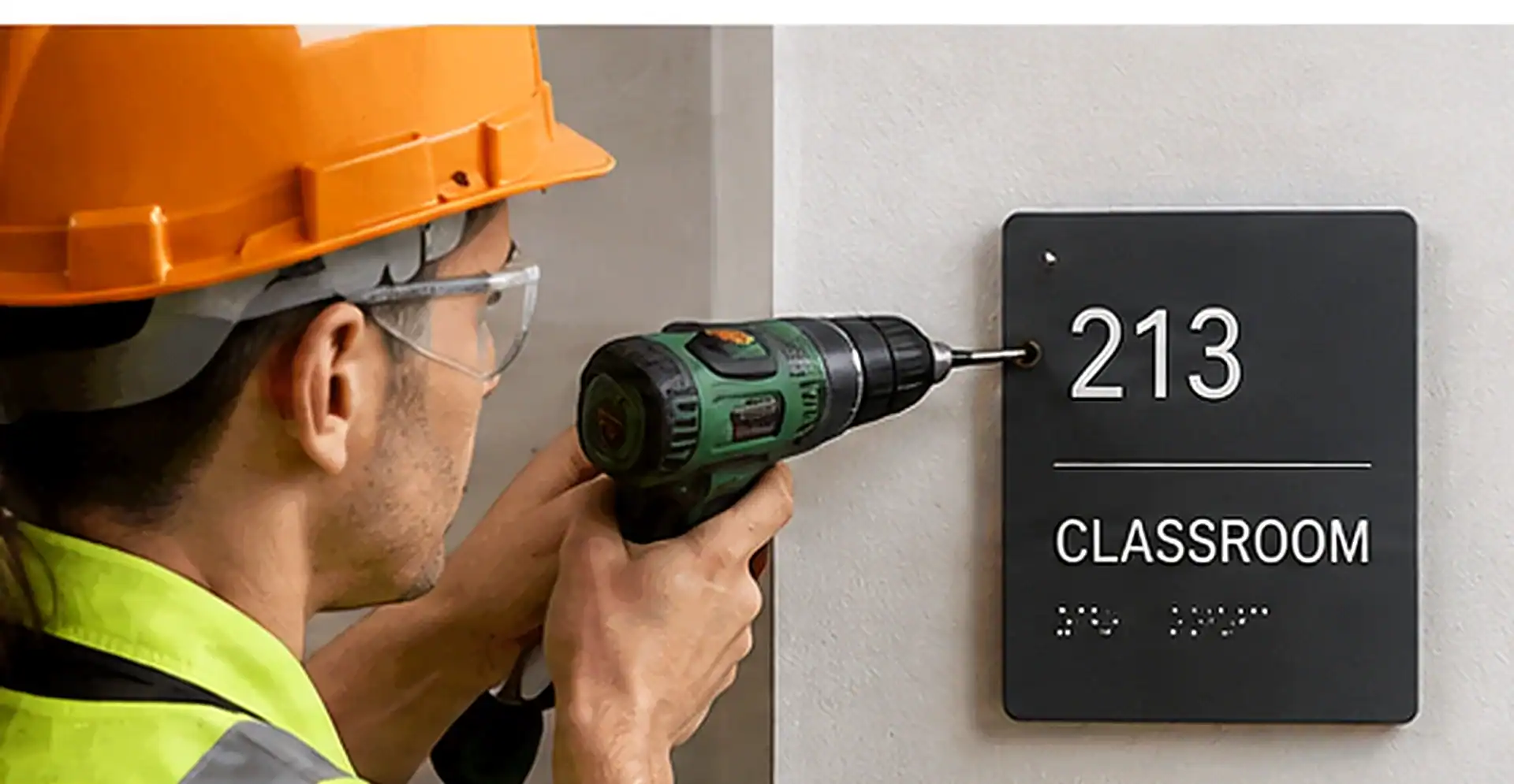 Installer mounting an ADA classroom identification sign